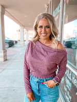 Ribbed off shoulder knit top with long sleeves and smocked waist in mauve.