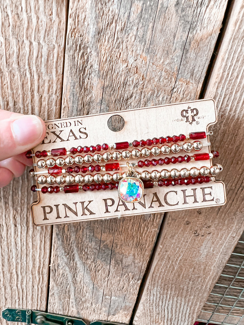 This beautiful PINK PANACHE bracelet set features five strands of burgundy and gold beads, showcasing a gorgeous 10mm cushion cut drop. The intricate yet delicate design make it a beautiful piece for any jewelry collection.